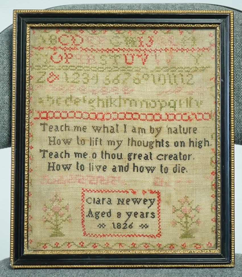 An early 19th century cross stitch alphabet sampler, dated 1826, by Clara Newey, aged 8 years. Worked in black, pink, green and red wool with a central religious verse. 23cm wide x 27.5cm high. Condition - some fading to
